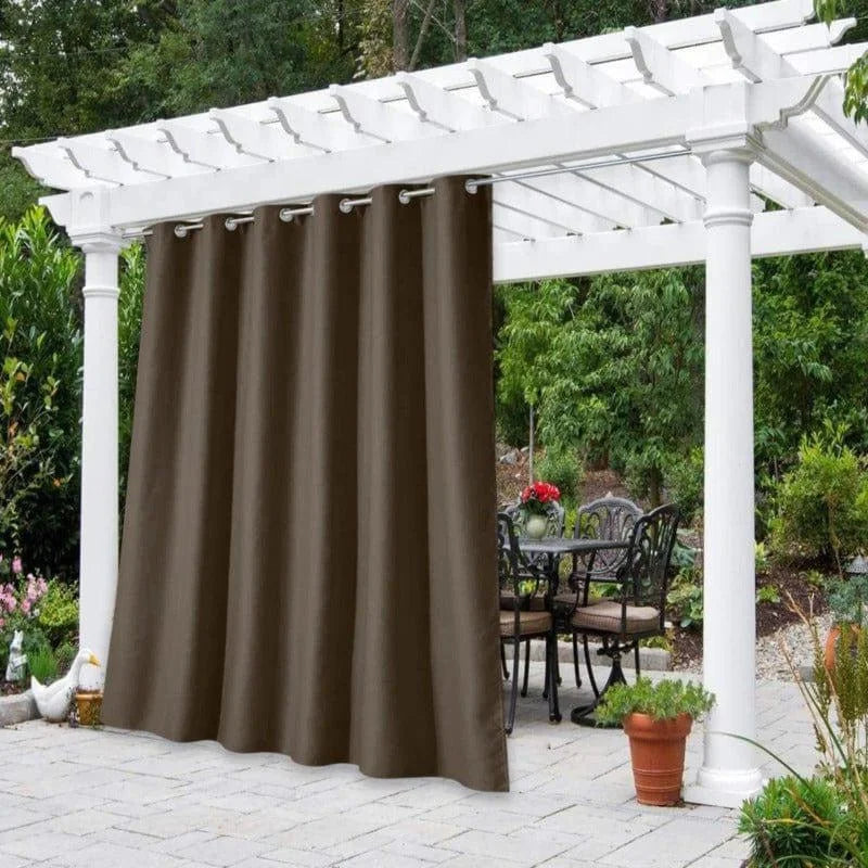 Rideau d'extérieur brun suspendu à une pergola blanche dans un jardin luxuriant. Créez un espace intime et élégant pour votre terrasse avec ce rideau d'extérieur, idéal pour ajouter une touche d'élégance et de protection contre le soleil. Profitez de votre espace extérieur avec style.