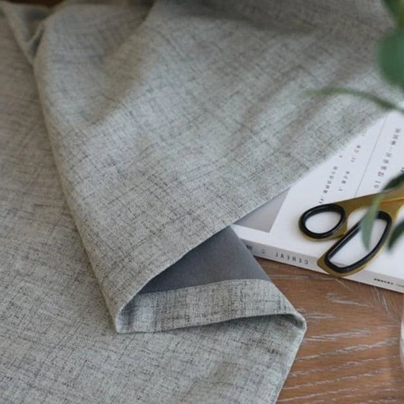 Tissu gris élégant posé sur une table en bois, accompagné de ciseaux dorés et d'un magazine. Décoration intérieure moderne et chic, idéal pour habiller vos espaces en ajoutant une touche sophistiquée et contemporaine. Accessoire parfait pour les designers et amoureux de la décoration.
