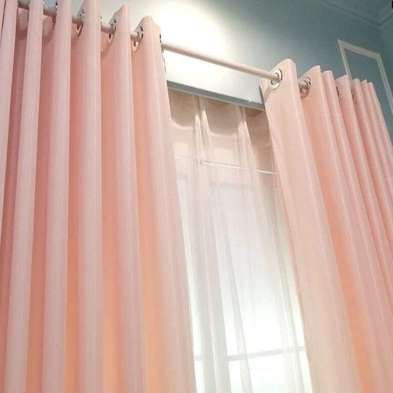 Rideaux élégants rose pastel décorant une fenêtre, apportant une touche de douceur et d'élégance à toute pièce intérieure. Idéals pour créer une ambiance chaleureuse et accueillante, ces rideaux sont parfaits pour le salon, la chambre ou la salle à manger. Profitez de la luminosité en journée tout en préservant votre intimité grâce à leur design raffiné et tendance.