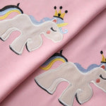 Tissu rose avec motif licorne brodé, couronné d'une couronne dorée, crinière arc-en-ciel, design enfantin, idéal pour décoration ou couture thématique.