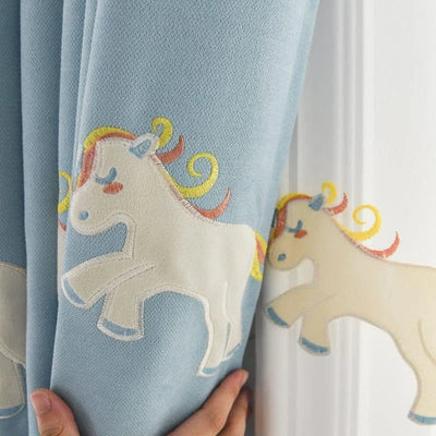 Rideaux enfantins avec motifs de licornes brodées sur fond bleu, idéals pour apporter une touche magique à la chambre d'enfant. Design coloré et ludique, parfait pour un décor de chambre moderne et amusant. Ces rideaux apportent une ambiance féerique et unique à l'espace de jeu des enfants.