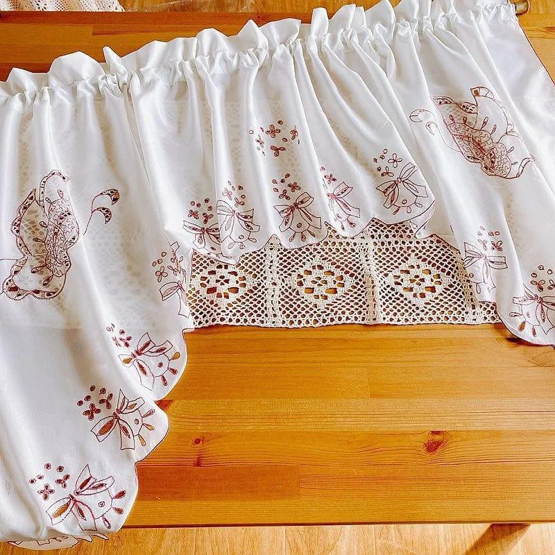 Rideau blanc décoratif avec motifs floraux brodés et détail ajouré, idéal pour ajouter une touche d’élégance à votre cuisine ou salon. Design raffiné et charme authentique pour illuminer vos espaces intérieurs avec style.