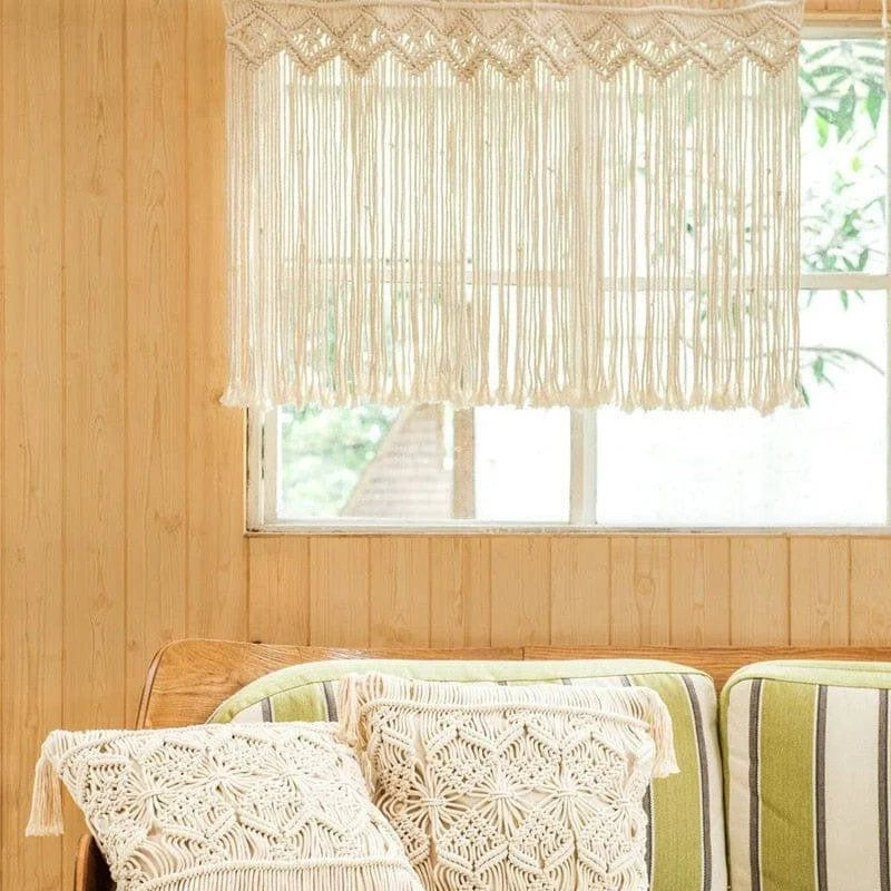 Décoration intérieure élégante : rideau bohème suspendu devant une fenêtre, complété par des coussins décoratifs sur un canapé. Idéal pour créer une ambiance chaleureuse et naturelle dans votre salon. Optimisez votre espace avec ce design tendance et raffiné.