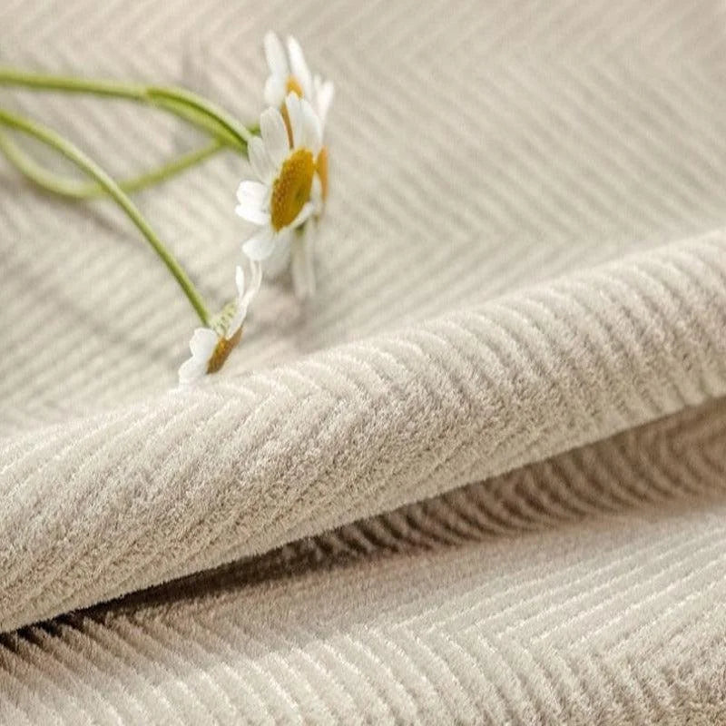 Image d'un tissu beige avec motif à chevrons, accompagné de fleurs blanches, idéal pour des décorations d'intérieur élégantes et raffinées.
