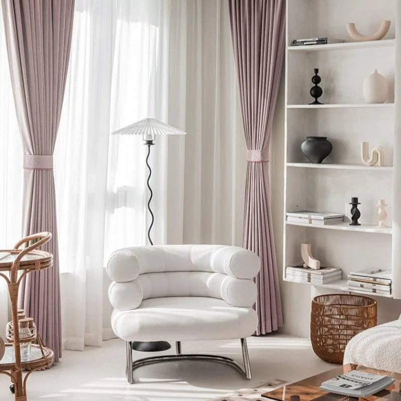 Fauteuil design blanc dans un salon minimaliste, accompagné de rideaux élégants et d'une étagère moderne. Décoration chic et contemporaine pour un intérieur raffiné. Ambiance lumineuse et épurée.