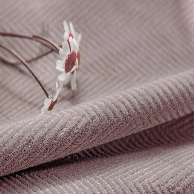 Tissu d'ameublement rose texturé avec motif chevron, parfait pour la décoration intérieure élégante. Fleur blanche ajoutant une touche délicate et naturelle. Idéal pour créations originales et modernes.
