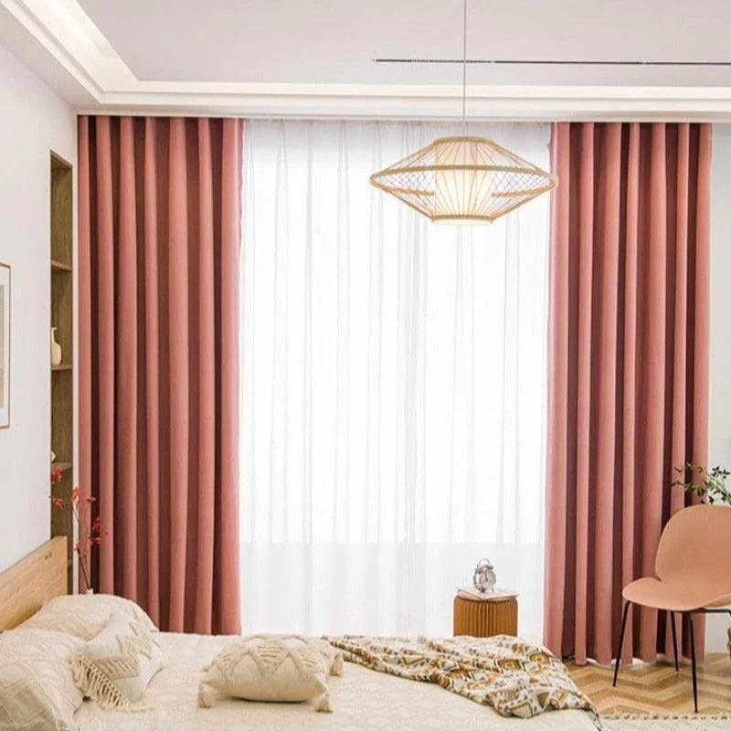 Chambre moderne avec rideaux rose pastel élégants, créant une ambiance chaleureuse et accueillante. Décoration intérieure raffinée avec un lit douillet, des coussins décoratifs et une chaise assortie. Lampadaire suspendu au design contemporain. Idéal pour une décoration chic et moderne.