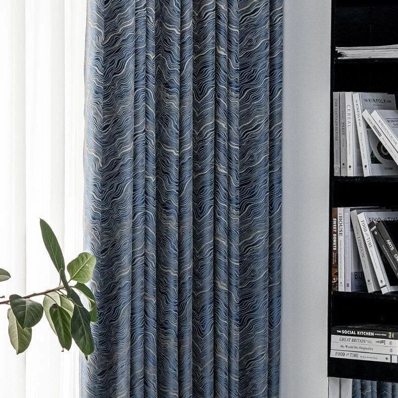 Rideaux élégants avec motifs ondulés bleus dans un intérieur moderne, lumière naturelle et bibliothèque en arrière-plan. Idéal pour un salon sophistiqué ou un espace de lecture.