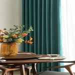 Rideaux verts élégants dans une salle à manger moderne avec table en bois et vase décoratif. Créez une ambiance sophistiquée et accueillante grâce à cette décoration intérieure raffinée. Idéal pour embellir votre maison avec des accessoires tendance et chaleureux.