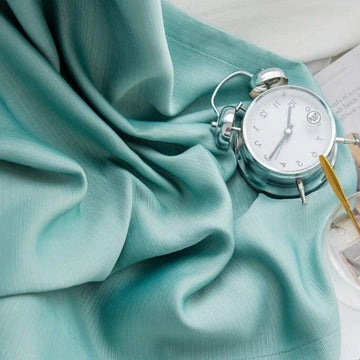 Réveil vintage argenté sur drap bleu pastel, alliant élégance et douceur pour une ambiance de chambre apaisante et stylée. Ajoutez une touche rétro à votre décoration intérieure.
