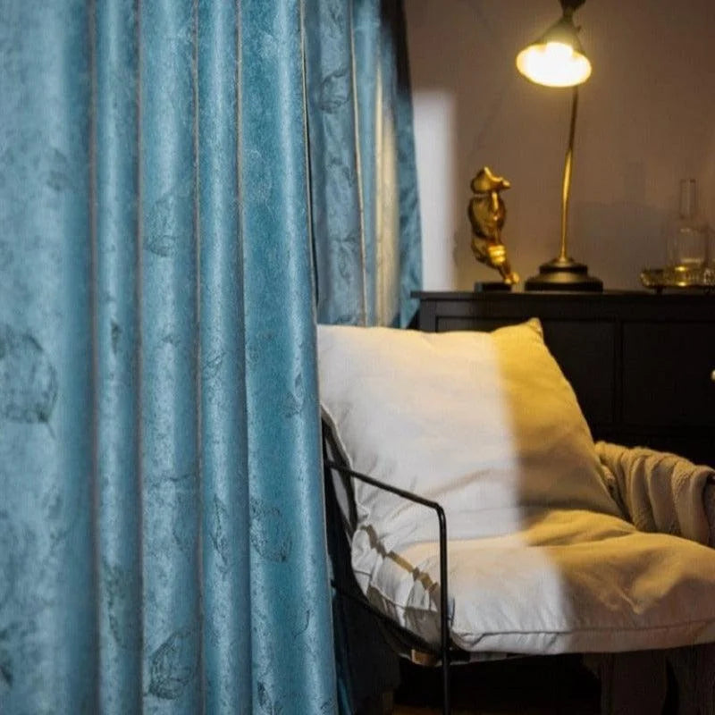 Rideaux bleus élégants pour salon, créant une ambiance chaleureuse et moderne. Le fauteuil confortable accentue un espace de détente idéal, rehaussé par un éclairage doux provenant d'une lampe design. Parfaite combinaison pour une décoration intérieure harmonieuse.