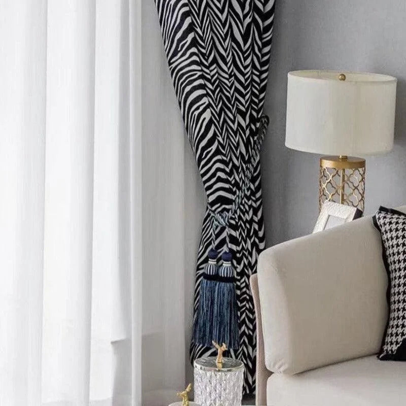 Rideaux élégants à motif zébré noir et blanc, rehaussant un salon moderne avec une décoration raffinée. Lampadaire doré et canapé clair complètent harmonieusement cet espace accueillant et élégant. Idéal pour une ambiance chic et contemporaine.