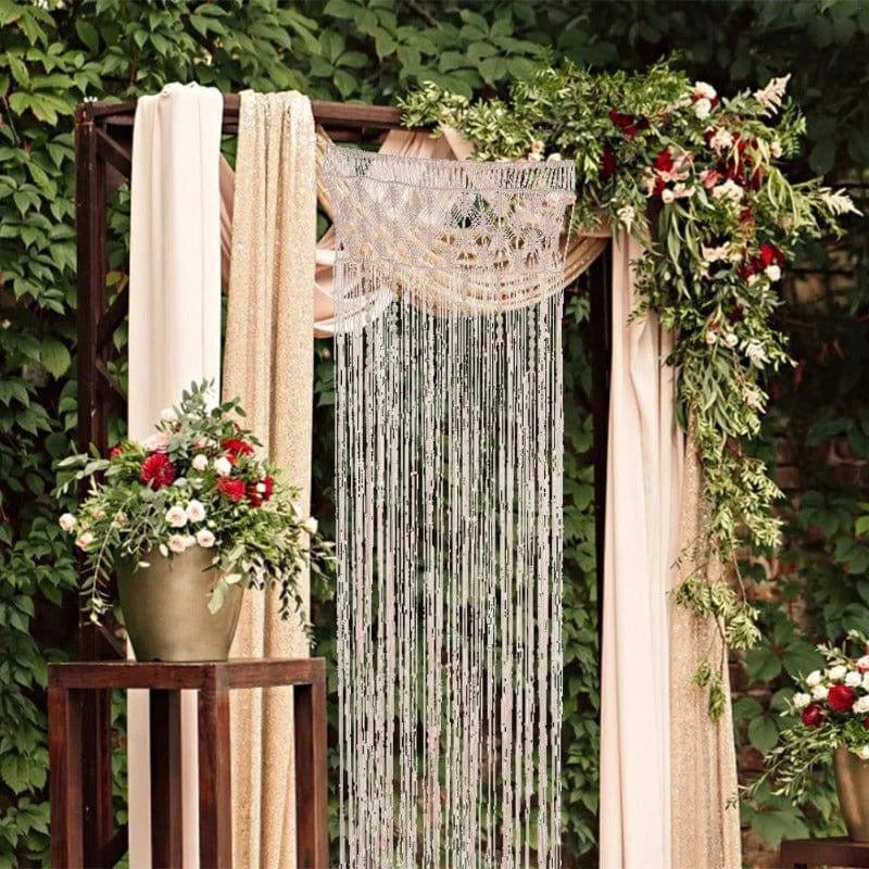 Décoration de mariage élégante avec arche florale ornée de roses rouges et blanches, idéale pour une cérémonie romantique en extérieur. Élément central avec rideaux drapés et suspension décorative en perles. Ambiance naturelle et sophistiquée pour un événement mémorable.