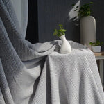 Rideau élégant à motifs chevrons gris et blanc, drapé devant une fenêtre, avec une décoration contemporaine. Idéal pour ajouter une touche de sophistication et de style moderne à n'importe quelle pièce. Composition en tissu de haute qualité, offrant un effet d'ombrage efficace. Accessoire de décoration intérieure, parfait pour salon, chambre ou bureau.