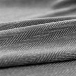 Texte alternatif SEO : "Gros plan d'un tissu de rideau à motif chevrons gris, idéal pour une décoration intérieure moderne et élégante. Ce rideau en textile de haute qualité offre une texture sophistiquée, parfaite pour habiller vos fenêtres avec style et raffinement."