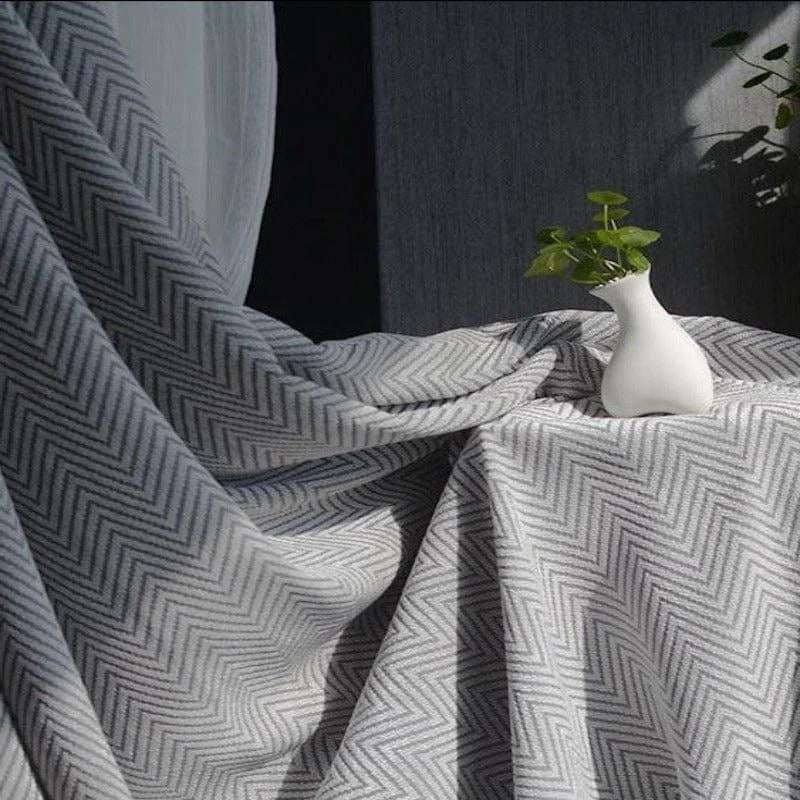 Rideau gris à motifs chevrons, idéal pour une décoration intérieure moderne et élégante. Ce tissu occultant et isolant offre une ambiance cosy tout en préservant votre intimité. Parfait pour le salon ou la chambre, il est mis en valeur par la douce lumière naturelle de la pièce. Accessoire déco raffiné, ce rideau complète à merveille votre espace de vie.