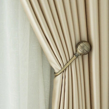 Rideau élégant beige attaché par un embrasse métallique, offrant une décoration raffinée et une lumière tamisée dans la pièce. Design moderne et chic parfait pour une ambiance cosy et contemporaine. Accessoire idéal pour ajouter une touche de sophistication à votre intérieur.
