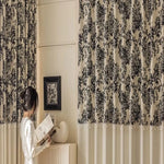 Rideaux élégants à motifs floraux noirs, apportant une touche sophistiquée à un intérieur moderne et chaleureux. Une femme lisant un livre ajoute une ambiance paisible et cosy à la pièce, parfaite pour créer un espace de détente et de confort. Décoration murale assortie, complétant harmonieusement le design de la pièce.