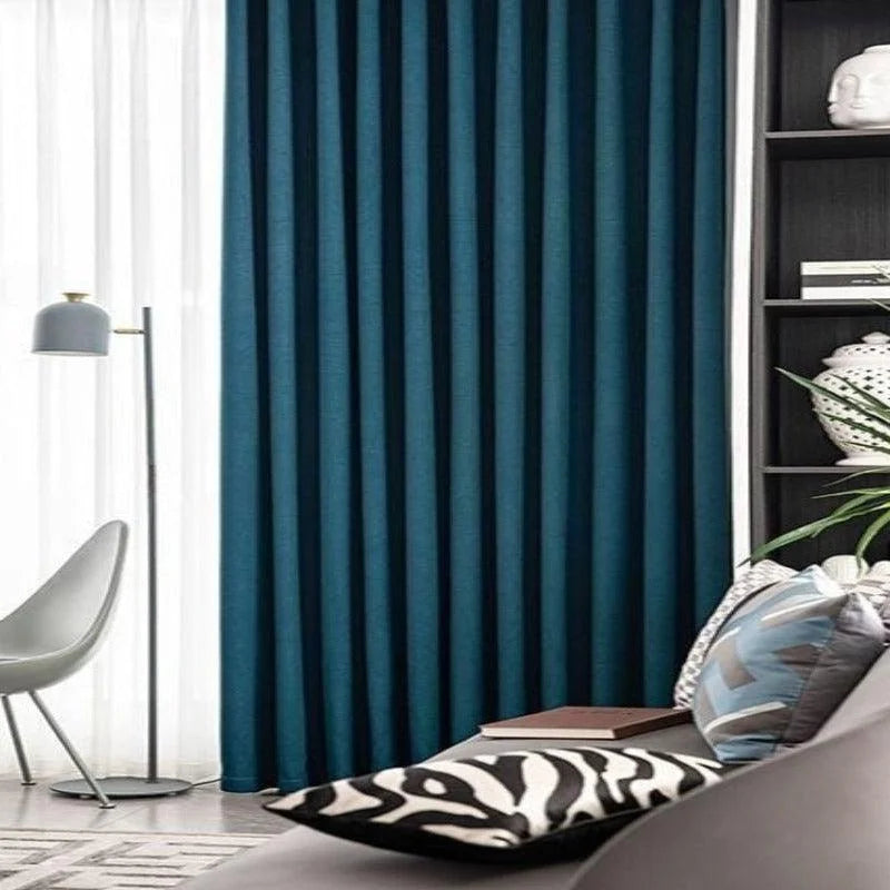 Rideau bleu élégant suspendu dans un salon moderne, accompagné d'une chaise design, d'une lampe en métal et de coussins décoratifs. Ajoutez une touche de sophistication et de confort à votre espace de vie avec cet accessoire de décoration intérieure, idéal pour filtrer la lumière et créer une ambiance chaleureuse. Transformez l'apparence de vos fenêtres grâce à ce rideau tendance.