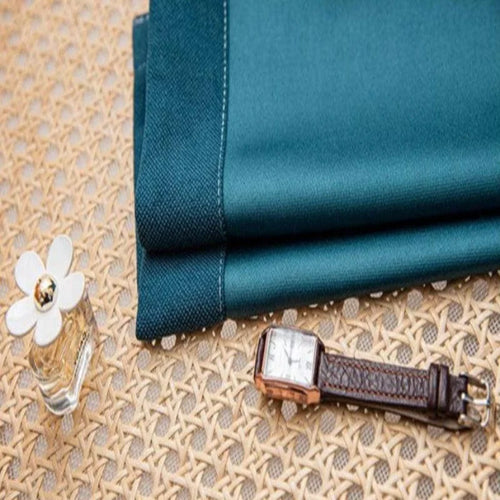 Montre élégante avec bracelet en cuir, posée sur un tissu bleu à côté d'un flacon de parfum sur une surface en rotin. Accessoires raffinés pour une touche de style sophistiqué. Ideal pour compléter une tenue chic et moderne.