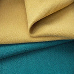 Deux tissus superposés, l'un de couleur jaune moutarde et l'autre de couleur turquoise, présentant une texture tissée serrée, idéale pour la confection de décorations intérieures ou d'accessoires de mode. Découvrez le design élégant et les teintes contemporaines pour sublimer vos projets créatifs.