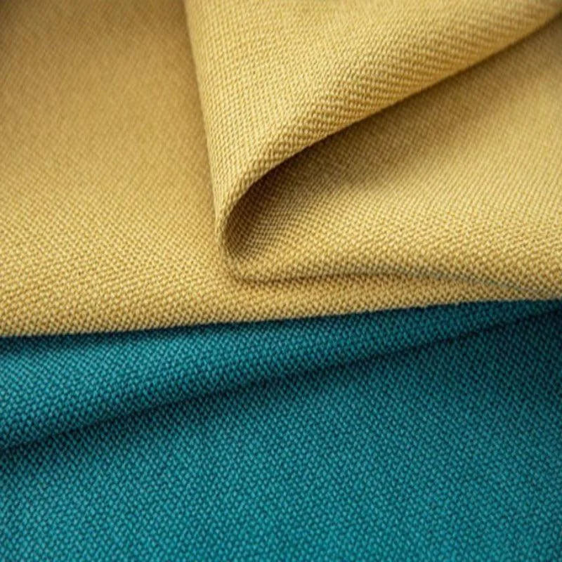 Deux tissus superposés, l'un de couleur jaune moutarde et l'autre de couleur turquoise, présentant une texture tissée serrée, idéale pour la confection de décorations intérieures ou d'accessoires de mode. Découvrez le design élégant et les teintes contemporaines pour sublimer vos projets créatifs.