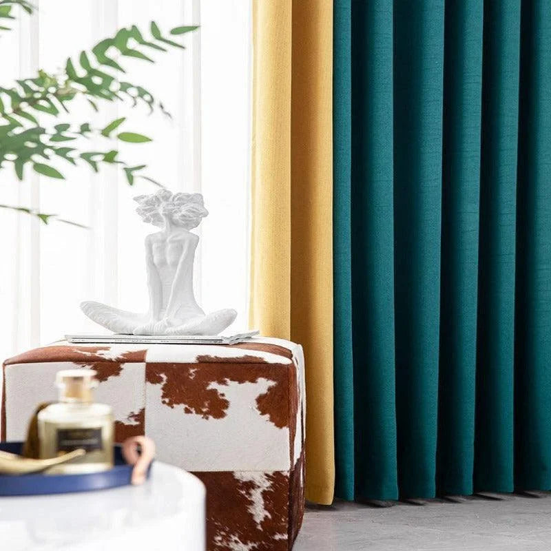 Décoration intérieure élégante avec rideaux bleu et jaune laissant entrer la lumière naturelle. Statue blanche au design moderne sur un pouf motif animal, ajoutant une touche artistique et contemporaine à l'espace. Accessoire parfumé sur table basse en premier plan. Idéal pour un salon sophistiqué.