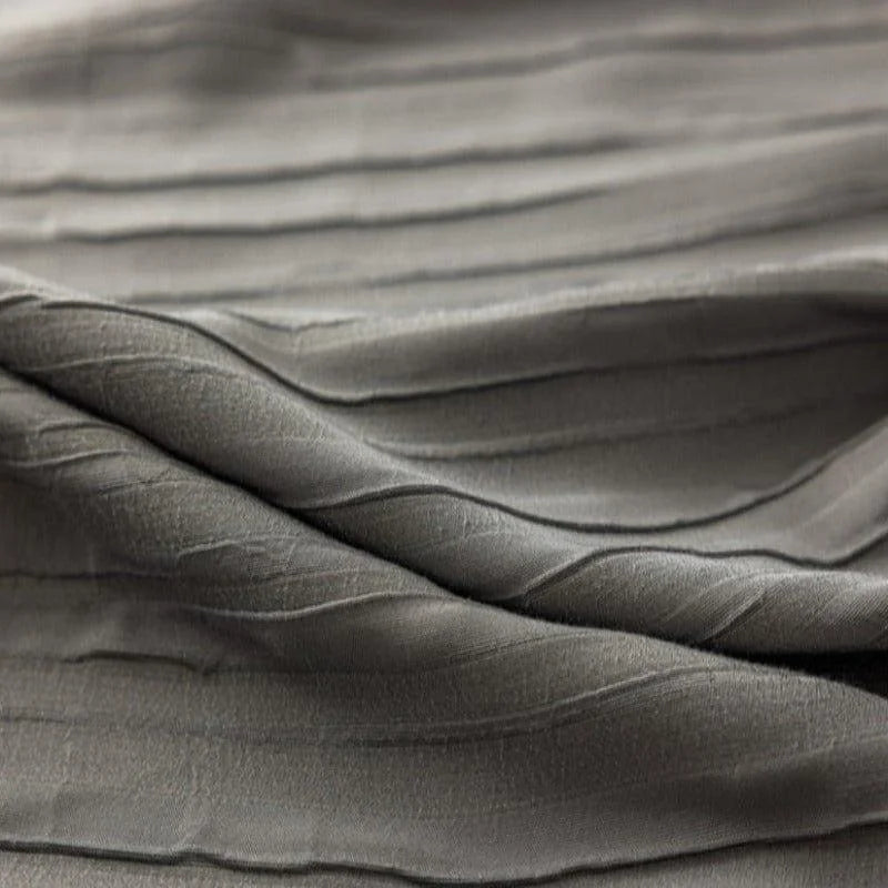 Texture de tissu gris aux plis élégants, idéale pour la confection de vêtements raffinés ou de décorations d'intérieur modernes. Ce design subtil ajoute une touche de sophistication à tout projet créatif.