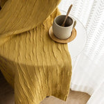 Image montrant un joli rideau jaune texturé drapé sur une table ronde transparente, à côté d'une tasse en céramique beige sur un sous-verre en bois, créant une ambiance apaisante et élégante pour un intérieur chaleureux.