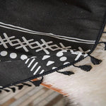 Tapis noir avec motifs géométriques blancs et bordures à franges, idéal pour apporter une touche ethnique et moderne à votre décoration intérieure. Parfait pour le salon ou la chambre à coucher, il s'intègre harmonieusement avec différents styles d'ameublement.
