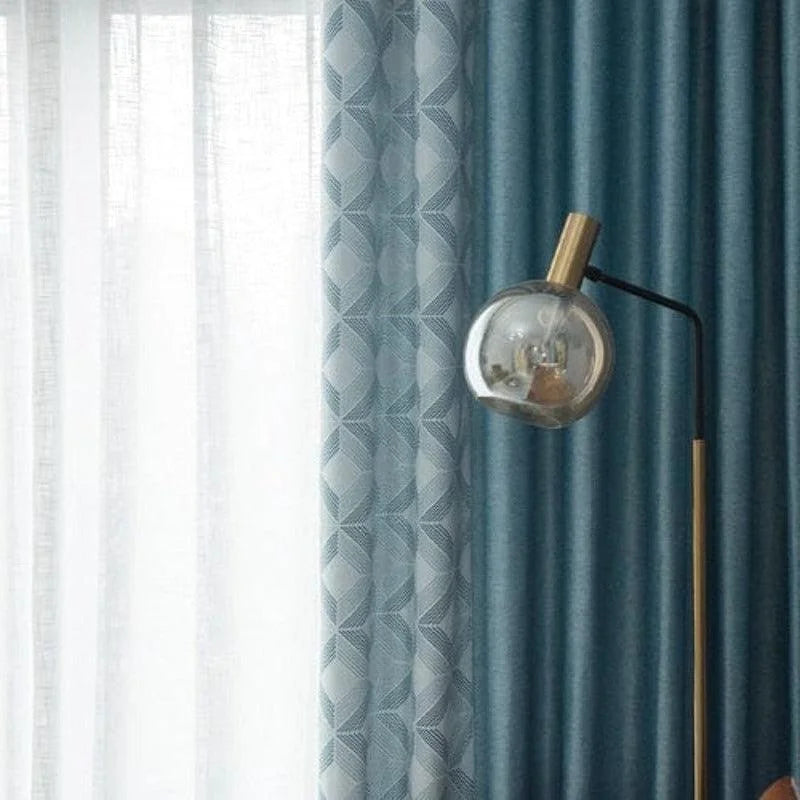 Lampe de salon moderne sur pied avec abat-jour en verre, mise en valeur par des rideaux bleus élégants, parfaits pour créer une atmosphère chic et contemporaine dans votre intérieur.