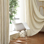 Chaise à bascule design moderne positionnée dans un salon lumineux avec de grandes fenêtres. Idéale pour un intérieur contemporain, elle s'harmonise parfaitement avec des rideaux beiges et un sol en bois clair. Parfaite pour un coin de lecture, cette chaise ajoute une touche élégante et confortable à votre espace de vie.