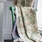 Plaid décoratif à motifs floraux multicolores drapé sur une chaise verte, idéal pour ajouter une touche élégante et chaleureuse à votre intérieur. Créez une atmosphère invitante dans votre salon ou chambre avec ce magnifique accessoire de maison.