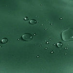 Image montrant une surface de couleur verte avec des gouttelettes d'eau éparpillées, illustrant l'effet imperméable et la résistance à l'eau. Idéal pour les vêtements de pluie ou les accessoires extérieurs offrant protection contre l'humidité.