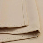 Gros plan sur un tissu beige plié avec une finition soignée et des bords détaillés. L'image montre les coutures précises et le design élégant, idéal pour la confection de vêtements ou de décoration intérieure. Parfait pour les créateurs à la recherche d'un textile de qualité aux lignes épurées et modernes.