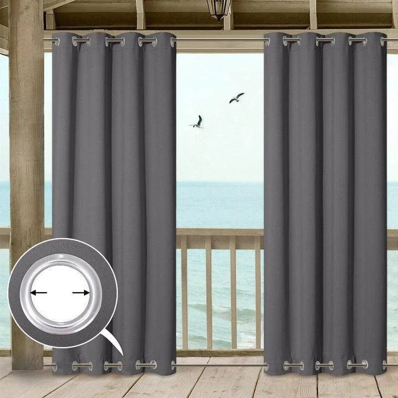 Rideaux occultants gris élégants sur terrasse avec vue sur mer. Idéal pour bloquer la lumière et offrir une ambiance apaisante. Les œillets métalliques assurent une installation facile et un tombé impeccable. Parfait pour une décoration intérieure moderne.