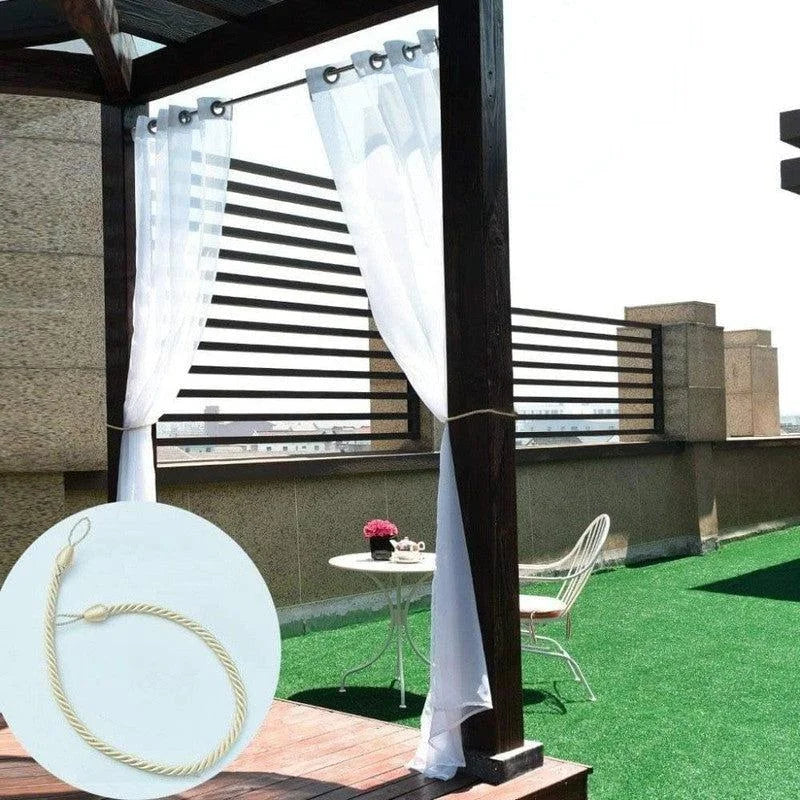 Balcon moderne avec rideaux blancs légers, offrant une touche d'élégance et d'intimité. Idéal pour créer un espace extérieur confortable. Le câble de fixation est visible, permettant un maintien sécurisé des rideaux en position. Terrasse ensoleillée avec mobilier de jardin élégant, parfait pour des moments de détente en plein air.