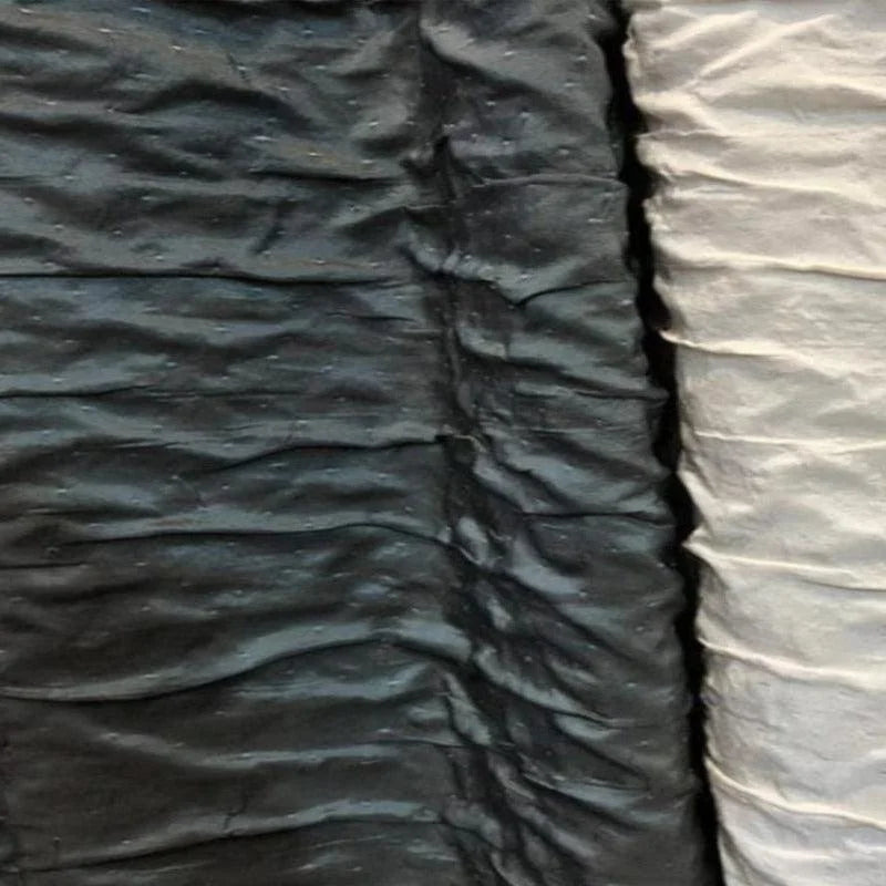 Image montrant des tissus plissés de couleur noire et blanche, disposés côte à côte, mettant en évidence un contraste élégant. Idéal pour la décoration intérieure ou les projets de couture, ces textures uniques ajoutent une touche moderne et sophistiquée.