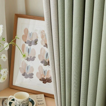 Rideaux élégants vert menthe dans un salon moderne, accompagnés d'un cadre artistique floral et d'une tasse à thé délicatement posée sur une table. Idéal pour ajouter une touche de fraîcheur et de sophistication à votre décoration intérieure.