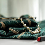 Foulard élégant vert à rayures dorées, accompagné d'un collier de perles chic. Accessoire de mode sophistiqué, idéal pour ajouter une touche de glamour à toute tenue. Parfait pour les occasions spéciales ou pour un style quotidien raffiné. Découvrez comment ce foulard et ce collier peuvent transformer votre look avec élégance et style.