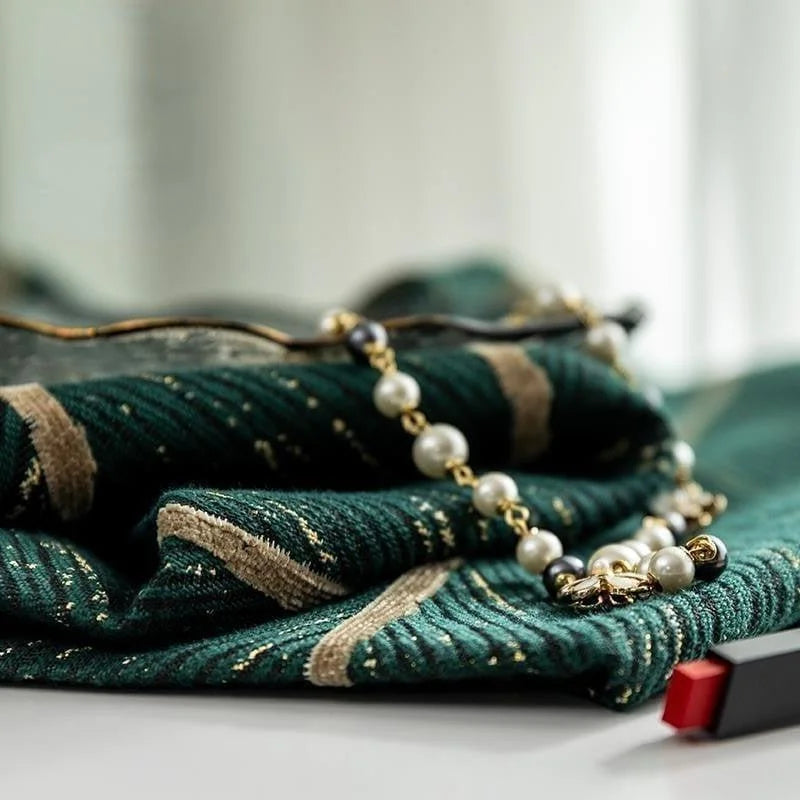 Foulard élégant vert à rayures dorées, accompagné d'un collier de perles chic. Accessoire de mode sophistiqué, idéal pour ajouter une touche de glamour à toute tenue. Parfait pour les occasions spéciales ou pour un style quotidien raffiné. Découvrez comment ce foulard et ce collier peuvent transformer votre look avec élégance et style.