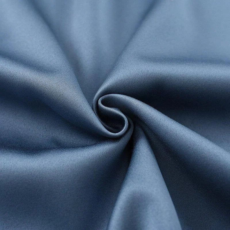 Texture de tissu bleu uni avec un effet satiné et un agencement en pli élégant, idéal pour les vêtements ou la décoration intérieure. Évoque un style raffiné et moderne.