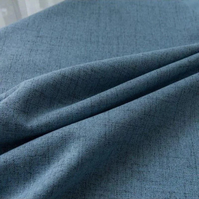 Alt texte : "Gros plan sur un rideau en tissu bleu texturé pour intérieur moderne - Idéal pour ajouter une touche élégante et sophistiquée à votre salon ou chambre. Rideau occultant de haute qualité, isolant thermique et facile à entretenir."