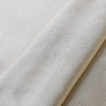 Image d'un tissu brodé clair avec des motifs floraux délicats, idéal pour la décoration intérieure ou la confection de vêtements élégants. Design raffiné et détails subtils pour un style intemporel et sophistiqué.