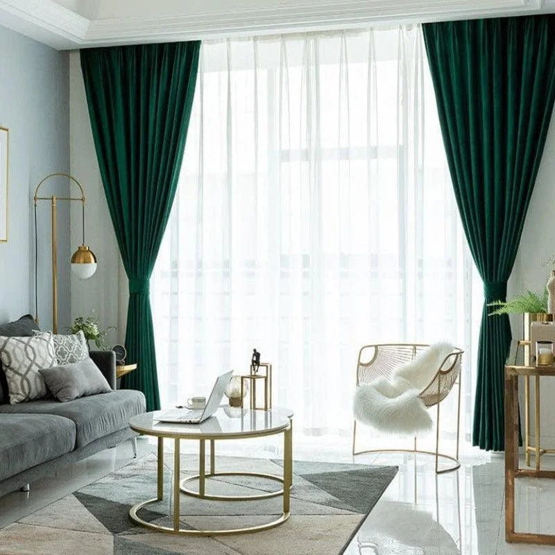 Salle de séjour moderne avec rideaux verts épais, offrant une ambiance élégante et lumineuse. Le salon est décoré avec un canapé confortable, une table en métal doré, et un fauteuil design, le tout accompagné d'un éclairage contemporain, créant un espace chaleureux et accueillant. Cette pièce est idéale pour les moments de détente et de convivialité en famille ou entre amis.