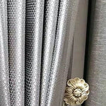 Rideau décoratif gris lumineux avec motif texturé et embrasse en forme de fleur, parfait pour ajouter une touche élégante à votre intérieur.
