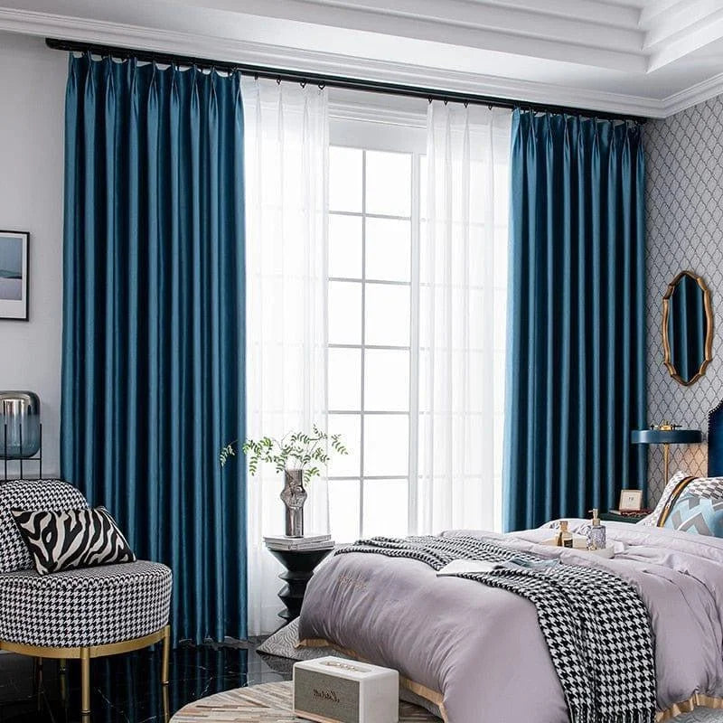 Chambre élégante avec rideaux bleu profond, apportant une touche de sophistication. Ces rideaux offrent un contraste parfait avec le décor moderne de la pièce, accentuant la lumière naturelle entrant par les grandes fenêtres. Idéal pour une ambiance chaleureuse et contemporaine, ce modèle transforme l'espace en un lieu cosy et chic.
