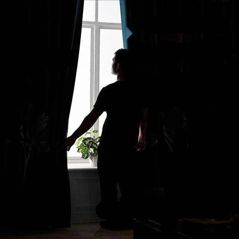 Personne près d'une fenêtre lumineuse, ouvrant un rideau sombre. Plante en pot sur le rebord, créant une atmosphère cosy, idéale pour un intérieur moderne. Capture l’essence de la décoration intérieure élégante et minimaliste.