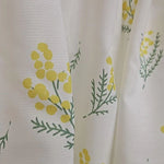 Rideau décoratif blanc avec motif floral jaune et vert mettant en vedette des branches de mimosa, idéal pour apporter une touche de fraîcheur naturelle à votre intérieur. Accessoire parfait pour le salon ou la chambre, ce rideau combine esthétique et fonctionnalité, offrant une ambiance lumineuse et printanière à votre espace de vie.