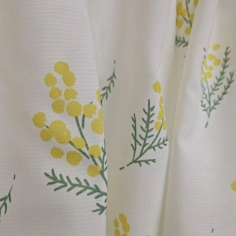 Rideau décoratif blanc avec motif floral jaune et vert mettant en vedette des branches de mimosa, idéal pour apporter une touche de fraîcheur naturelle à votre intérieur. Accessoire parfait pour le salon ou la chambre, ce rideau combine esthétique et fonctionnalité, offrant une ambiance lumineuse et printanière à votre espace de vie.